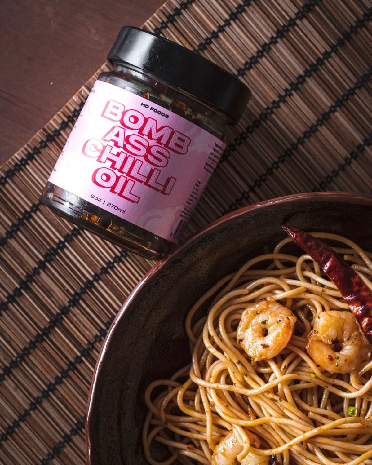 Jar of BACO chilli oil next to a bowl of chilli prawn spaghetti