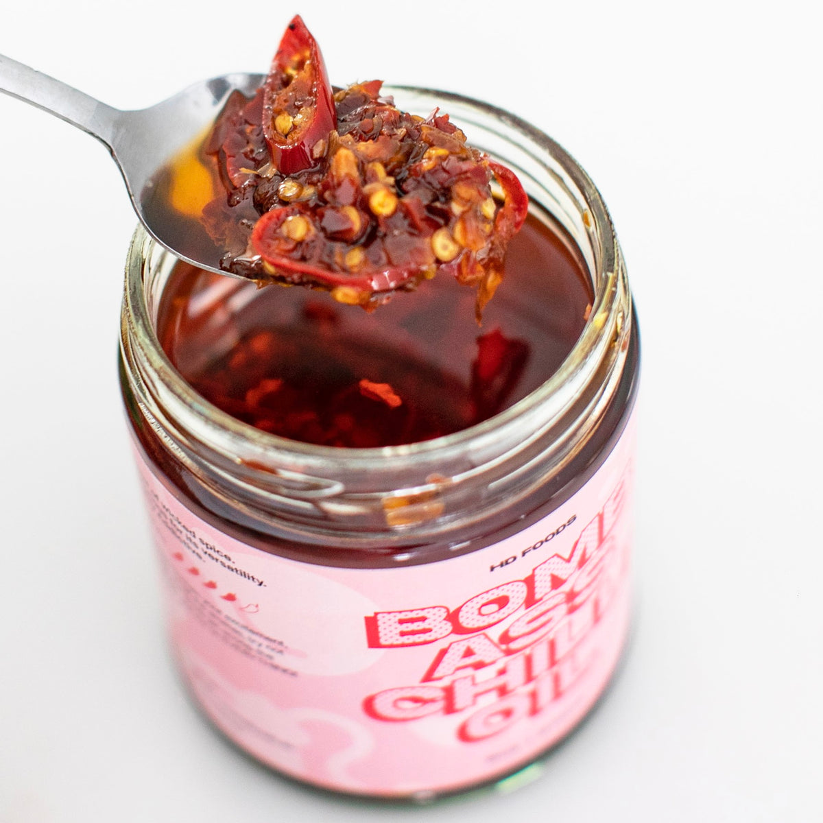 Spoonful of BACO chilli oil with crispy chilli and garlic, held over the jar